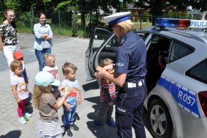 Spotkanie policjantów z przedszkolakami, policjantka wręcza dzieciom odblaski.