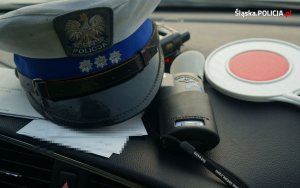 policyjna czapka obok tarczy do zatrzymywania pojazdów na podszybiu samochodu