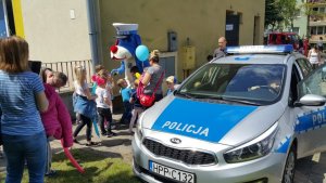 dzieci i młodzież na festynie w Żłobku Miejskim Reksio stoją przy radiowozie i oglądają pojazd