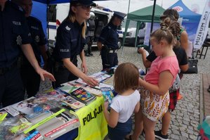 policjanci przy stolikach rozmawiają z dziećmi o bezpiecznych wakacjach