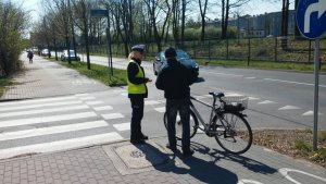 policjantka z ruchu drogowego rozmawia przed przejściem dla pieszym z rowerzystą