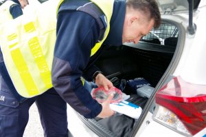 policjant układa otrzymane środki ochrony w bagażniku radiowozu