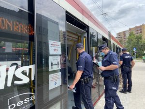 dwóch policjantów wchodzi do tramwau, trzeci rozmawia z mężczyzną