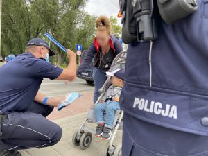 policjant wręcza odlblask kobiecie z dzieckiem
