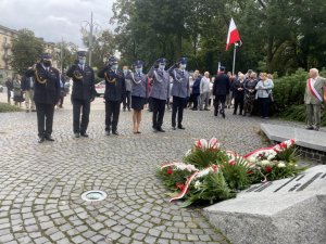 policjanci i strażacy oddają honor pod pomnikiem ks. Jerzego Popiełuszki