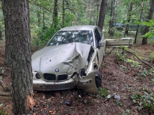 samochód BMW z uszkodzonym przodem po uderzeniu w drzewo