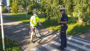 policjantka tłumaczy młodemu rowerzyście zasady przeprowadzenia egzaminu