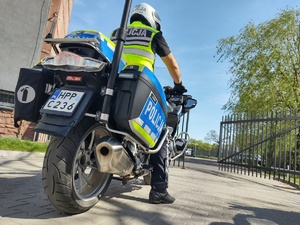 Policjant na motocyklu czeka przy otwierającej się bramie
