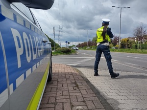 Policjantka stoi przy drodze obok radiowozu
