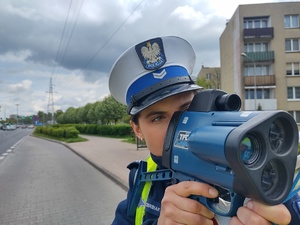 Policjantka mierzy urządzeniem, które trzyma w rękach na wysokości wzroku